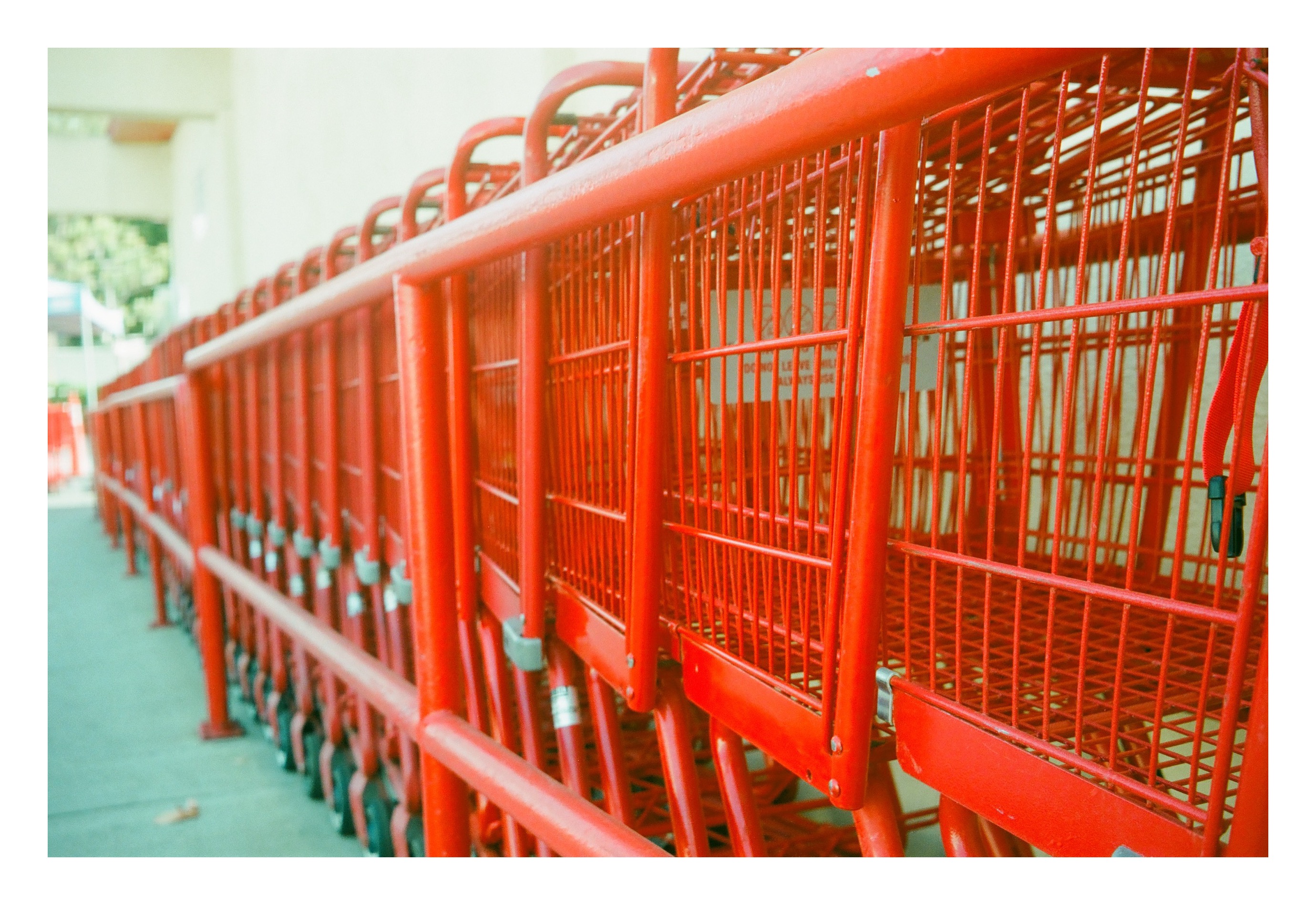 A long row of nested red shopping carts photographed in shallow depth of field, receding into soft focus.